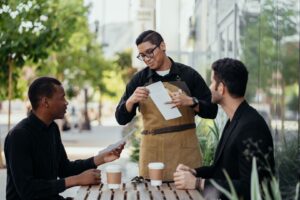 Un serveur explique un document à deux collègues autour d’une table